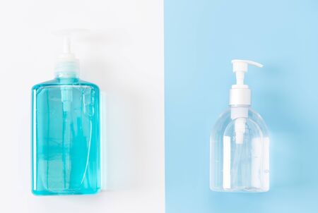 White and blue bottles of sanitizer or liquid soap for hand hygiene to protect from corona virus over two tone background,flat layの写真素材