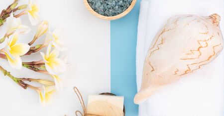 Spa massage, exotic tropical plumeria flowers ,coconut soap,scrub,sea shells, white towels and Himalayan salt  on blue background,flat layの写真素材
