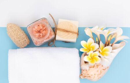 Spa massage, exotic tropical plumeria flowers ,coconut soap,scrub,sea shells, white towels and Himalayan salt  on blue background,flat layの写真素材
