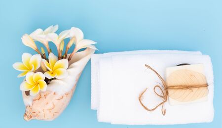 White towel and beautiful frangipal or plumeria spa flower  in sea shell vase and coconut soap on blue background,flat layの写真素材
