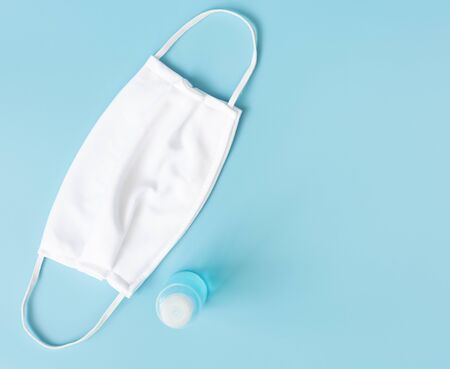 White mask for wearing germ protection  and gel alcohol or hand sanitizer spray bottle for washing hand  to protect from corona virus set on blue background,top viewの写真素材
