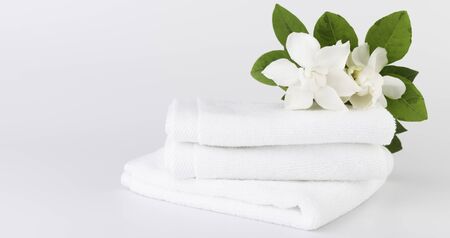 Spa and health care concepts setup with stack of white towels  and tropical Gardenia flowers on white backgroundの写真素材