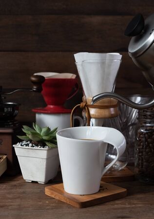 Coffe drip set with,roasted beans,kettle,grinder,white cup and flower pot on wood table and backgroundの写真素材