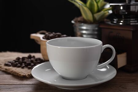 White coffee cup,coffee grinder and roasted beans  in glass jar on wooden table with dark backgroundの写真素材