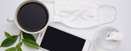 Work from home New Normal concept due to Covid-19 or Coronavirus with antibacterial hand gel, cloth mask,coffee cup, and  mobile phone on white background,flat layの写真素材