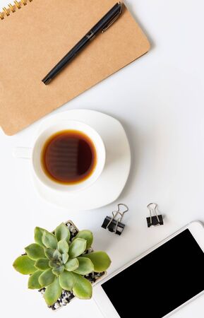 Workspace compositon  with, coffee cup,notebook,pen ,csmart phone and green leaves pot with space on white background,top viewの写真素材