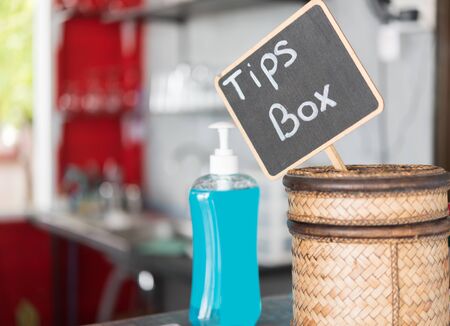 Tip box and hand sanitizer on table in restaurantの写真素材