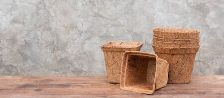 Ecology flower pots made from coconut fiber on wooden table with cement wall backgroundの写真素材