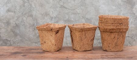 Ecology flower pots made from coconut fiber on wooden table with cement wall backgroundの写真素材
