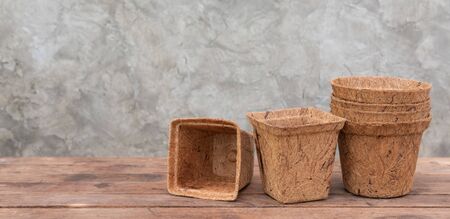 Ecology flower pots made from coconut fiber on wooden table with cement wall backgroundの写真素材