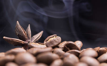 Aroma roasted coffee beans and star anis with smoke rising over purple dark  backgroundの写真素材