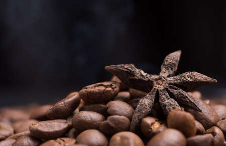 Aroma roasted coffee beans and star anis with smoke rising over dark backgroundの写真素材