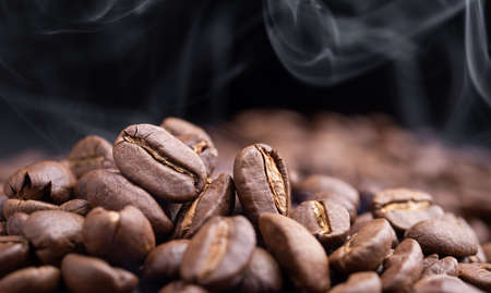 Aroma roasted coffee beans with smoke rising over dark backgroundの写真素材