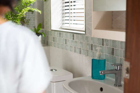 Blurred woman in modern bathroom or restroom with hand sanitizer to protect from coronavirusの写真素材