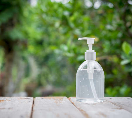 White hand sanitizer or alcohol gel pump bottle on wooden top with green nature backgroundsの写真素材