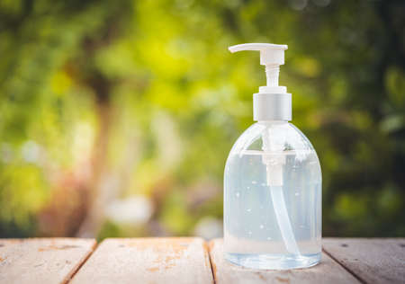 White hand sanitizer or alcohol gel pump bottle on wooden top with green nature backgroundsの写真素材