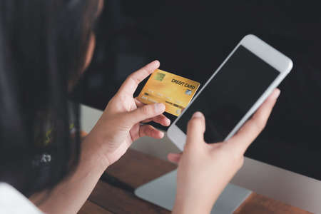 Woman's hands holding a credit card and using smart phone for online shopping  or e commmerceの写真素材