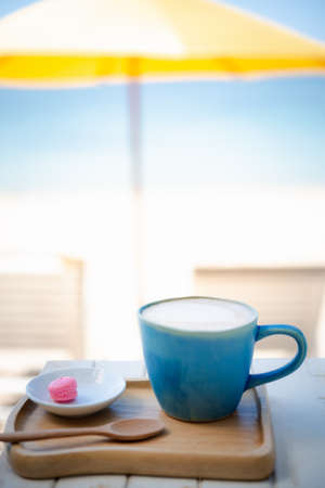 Summer blue coffee Latte cup by the beach  with yellow umbrella backgroundの写真素材