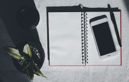 Workspace with mobile phone,notebook,pen,coffee cup and house plant on white background,top viewの写真素材