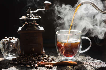 Steam coffee cup with grinder,beens,kettle and glass cup on grunge wood table dark backgroundの写真素材