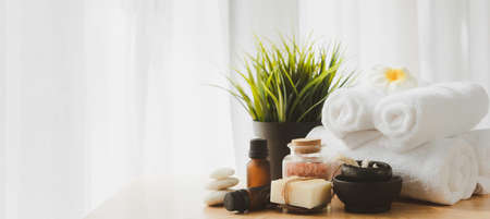 Spa wellness concept,zen stone,white candle,milk soap,salt,towel,flowers and oil massage bottle on wood table white backgroundの写真素材