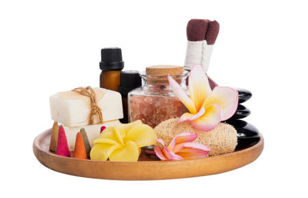 Spa products with  organic soap,luffa scrub,compress ball,pink salt,black stones, and beautiful plumerai flower on wooden tray isolated on white background with clipping path.の写真素材