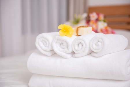 White towels,soap,candle and beautiful frangipani or plumeria flowers in bamboo wooden basket  on modern white bedroomの写真素材
