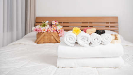 Spa wellness concept with white towels,candle,milk soap,beautiful frangipani  flowers in bamboo wooden basket  on modern white bedroomの写真素材
