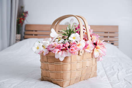 Beautiful frangipani or plumeria flowers in bamboo wooden basket  on modern white bedroom,welcome flowerの写真素材