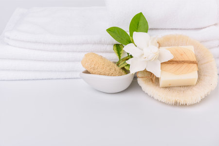 Spa and health care concepts setup with stack of white towels and tropical Gardenia flowers  milk soap luffa scrub on white backgroundの写真素材