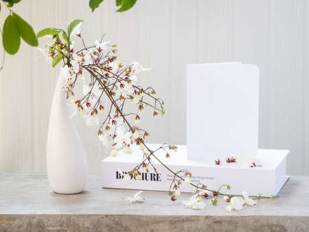 Mock up white  invitation card  and beautiful Nodding Clerodendron flowers in modern vase set on concrete table with white wood background,greeting card in soft tone still lifeの写真素材