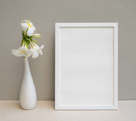 Mock up poster white frame and beautiful Plumeria or Frangipani tropical floral in modern white vase...