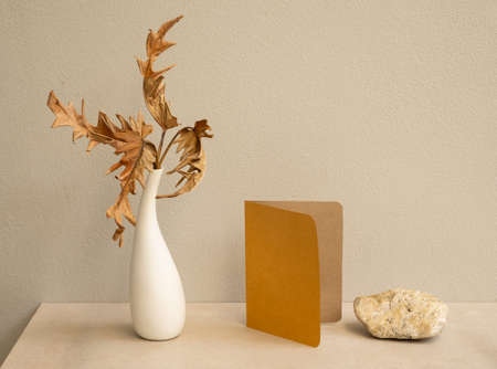 Mock up invitation brown cards and exotic Philodendron dry leaves in modern vase on marble table with concrete background,greeting card in earth tone still lifeの写真素材