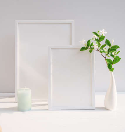 Mock up poster white frame and beautiful Gardenia tropical floral in modern white vase decor with green candle on beige table and cement wall background with long shadowの写真素材