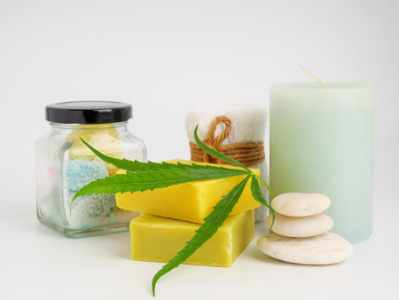 Spa hemp extract products with cannabis leaf soap bar and  white towel stone candle on white backgroundの写真素材