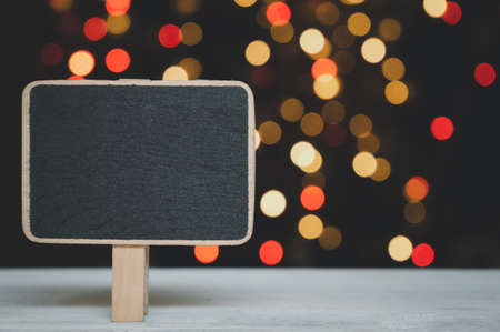 Blank blackboard for massage on white wood table with colorful bokeh backgroundの写真素材