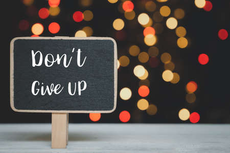 Do not Give up wrote on  blackboard over white wood table with colorful bokeh backgroundの写真素材