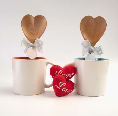 Cup of love,Two coffee cups with red heart icon  and wooden spoon on white backgroundの写真素材