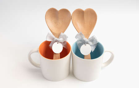 Cup of love,Two coffee cups with wooden spoon in  heart shape on white backgroundの写真素材
