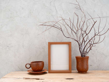 Teak wood frame mock up,coffee cup  and coral in coconut vase on wooden table  with loft concrete wall background,space for productsの写真素材