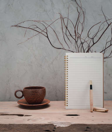 Coconut coffee cup ,brown notebook and coral in wood  vase on teak wooden table  with loft concrete wall background,space for productsの写真素材