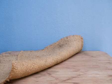 Sackcloth,burlap hessian  arrange on wooden table and blue cement wall background  with copy spaceの写真素材