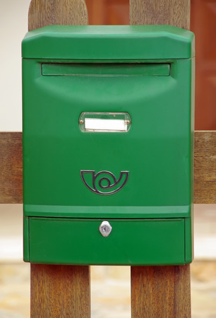 A green plastic mailbox mounted on a wallの写真素材