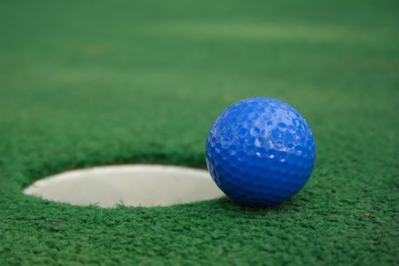 A miniature golf ball near the holeの写真素材