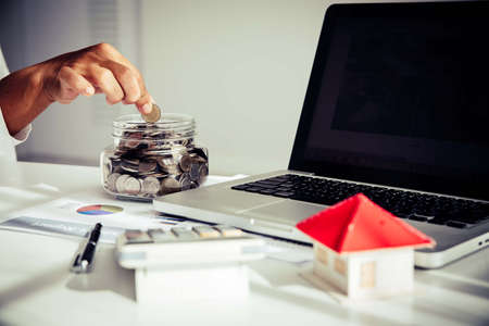 Business man putting coin increase on coins stacking with house model while preparation to saving for property investment and house mortgageの写真素材