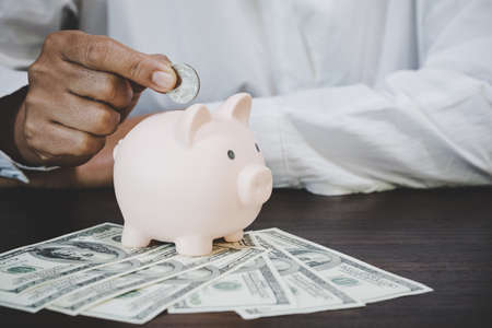 woman hand putting money coin into piggy for saving money wealth and financial concept.