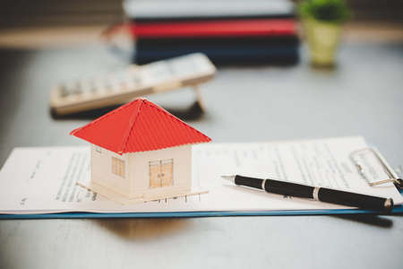 real estate purchase contract with architectural model and calculator