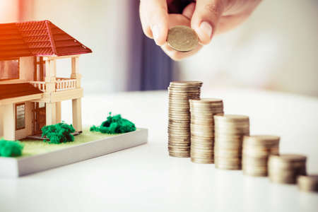 Business man putting coin increase on coins stacking with house model while preparation to saving for property investment and house mortgageの写真素材