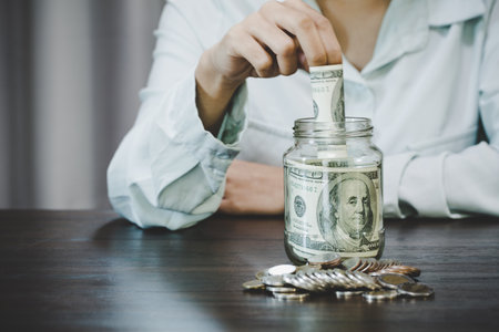 Woman holding dollar bills,  she is managing to divide the money to save money and invest it to make...
