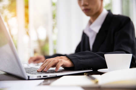 Close up of asian businessman surfing the internet, searching information on laptop computer and digital tablet pc, online working from home office, telecommuting. Freelancer working on computerの写真素材